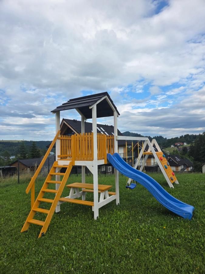 Drewniany plac zabaw ze zjeżdżalnią na trawie