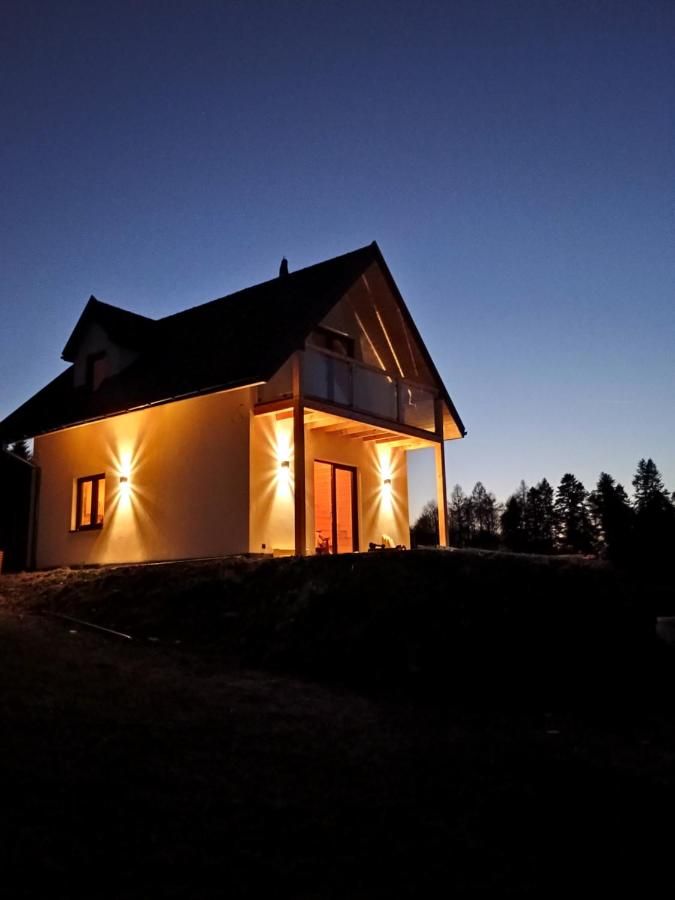 Dom nocą, ściany oświetlone ciepłym światłem lamp